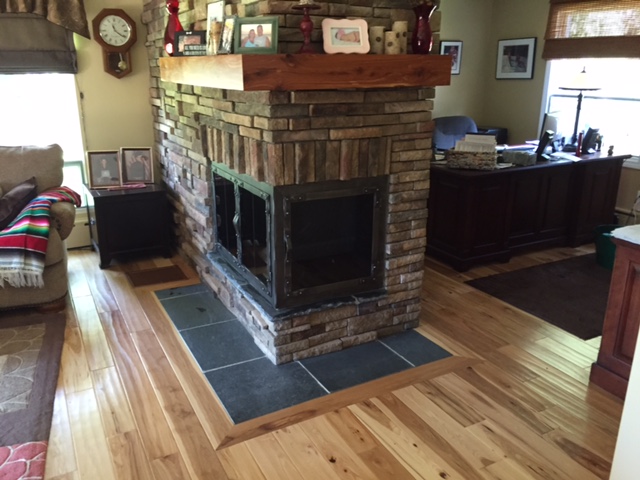 double sided gas fireplace with custom stone surround and wooden mantel in living room as room divider