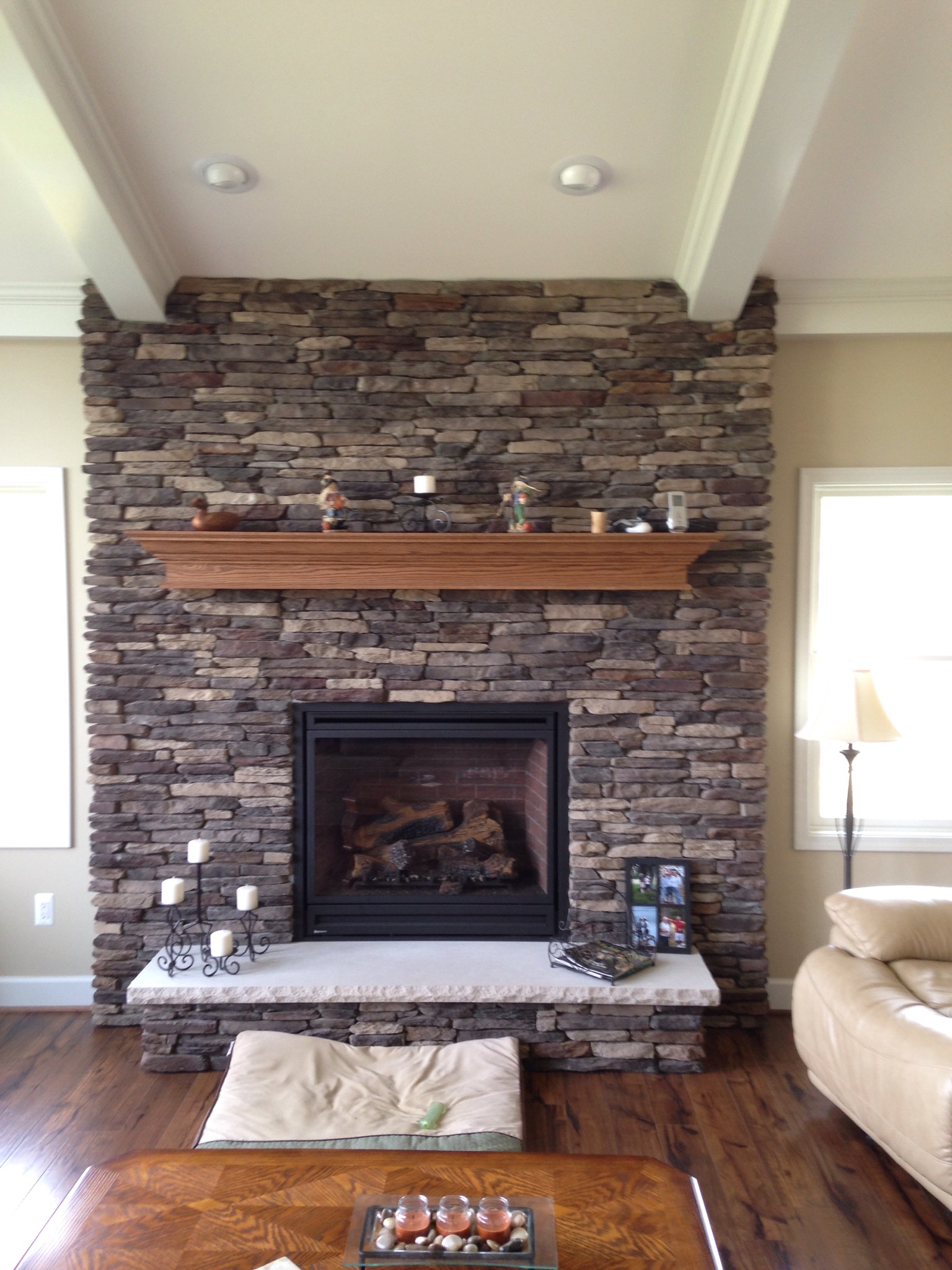 gas fireplace with dark stone surround and light wood mantel