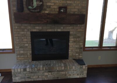 gas fireplace insert with stone surround and thick wooden mantel