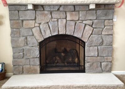 gas fireplace with gray stone surround and stone mantel