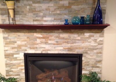 gas fireplace insert with light stone surround and wooden mantel