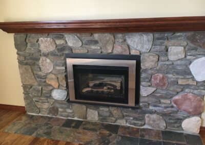 gas fireplace with chunky stone surround and dark wood mantel