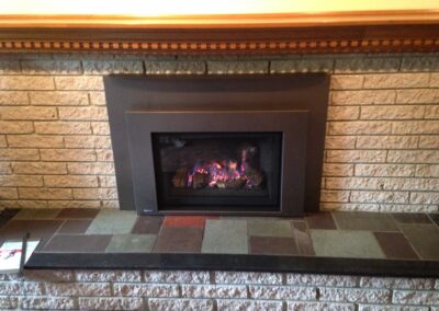 gas fireplace insert with light stone surround and wooden mantel