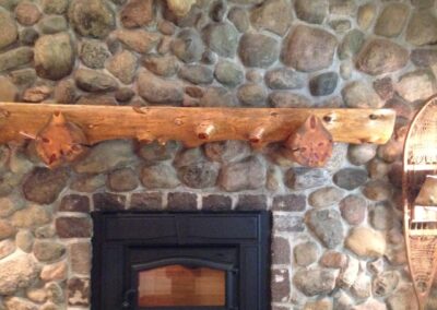 gas fireplace insert with chunky oval stone surround and natural log mantel for cabin