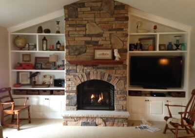 gas fireplace with light stone surround and small mantel