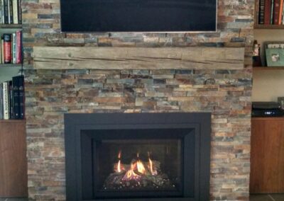 gas fireplace with custom stone surround and light wood floating mantel