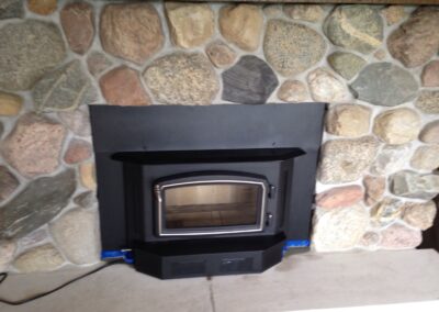 gas fireplace insert with chunky stone surround and wooden mantel