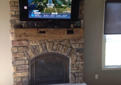 gas fireplace with stone surround and wooden mantel
