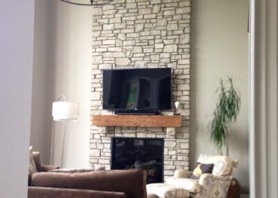 gas fireplace with custom light stone surround and wooden mantel in living room
