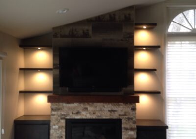 gas fireplace with light stone surround, wooden mantel, and custom shelves