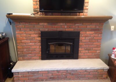 wood-burning fireplace with brick surround and light wooden mantel