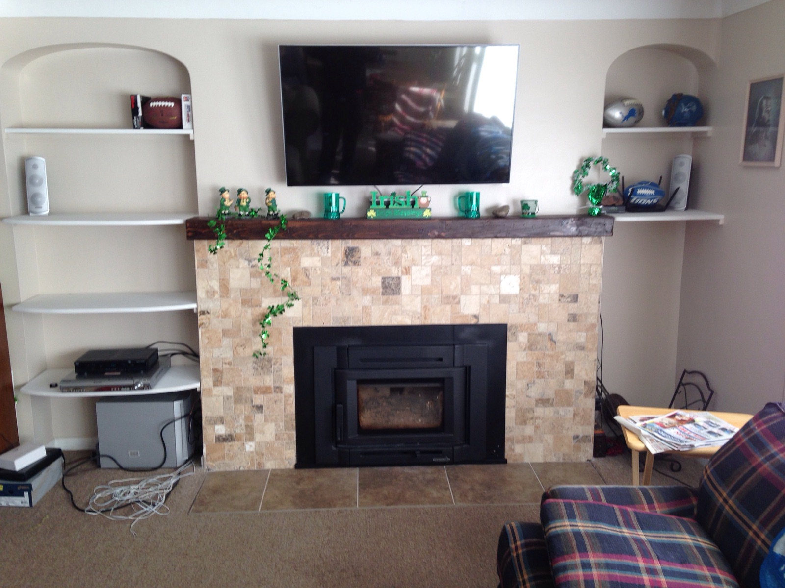 gas fireplace with light stone surround and wooden mantel