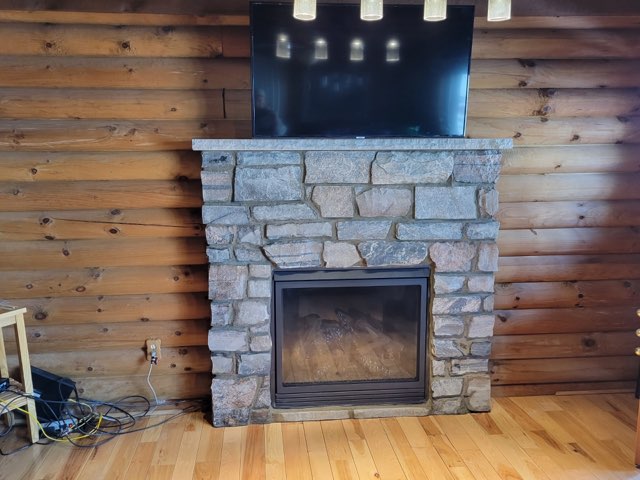 electric fireplace with custom stone surround and glass doors in cabin