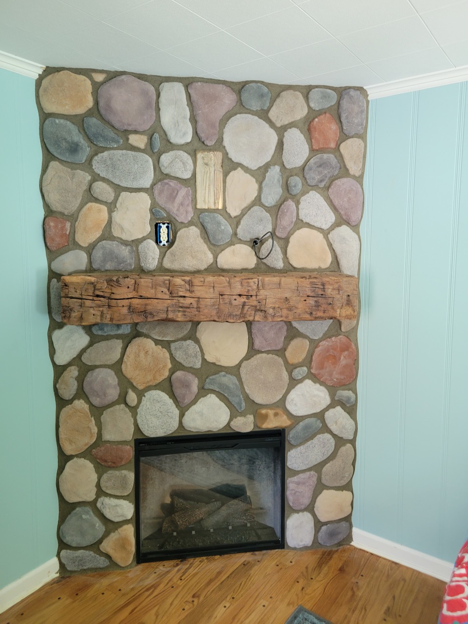 corner electric fireplace with custom stone surround and light wood mantel
