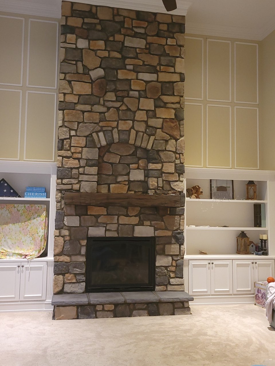 gas fireplace with custom stone surround and floating wooden mantel